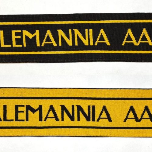 Two TSV Alemannia Aachen scarves laid side by side: one black with yellow lettering and fringed ends, and one yellow with black lettering and fringed ends, each featuring the club crest at the ends.