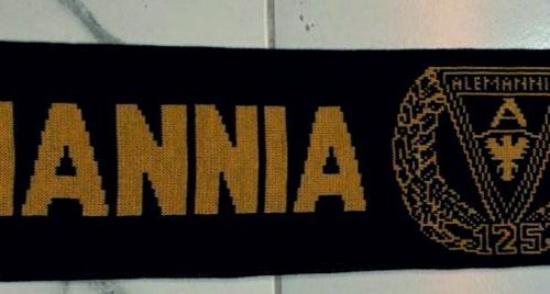 Black scarf with yellow 'Alemannia Aachen' lettering and central crest, ends with triangular logos on each side.