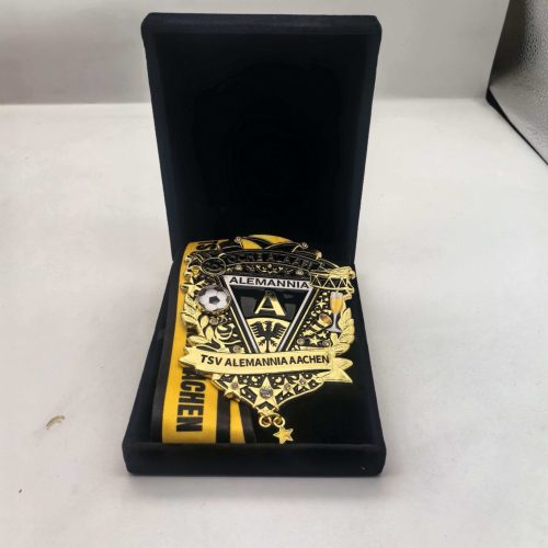 Golden championship belt in a black display box, with a black-and-yellow ribbon reading TSV Alemannia Aachen.