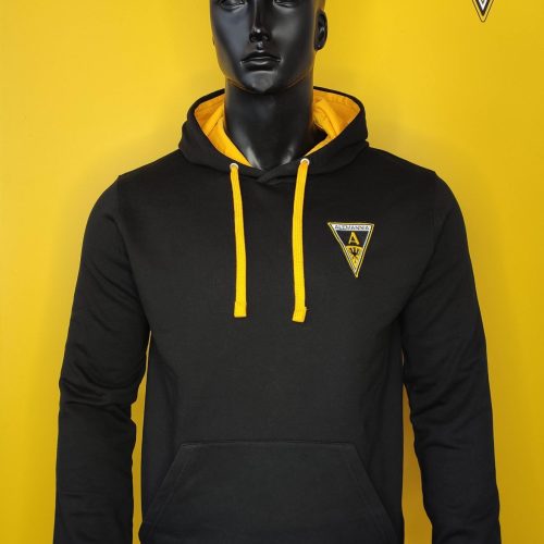 Mannequin wearing a black hoodie with yellow interior hood and drawstrings, yellow backdrop with Alemannia logo on the chest patch.