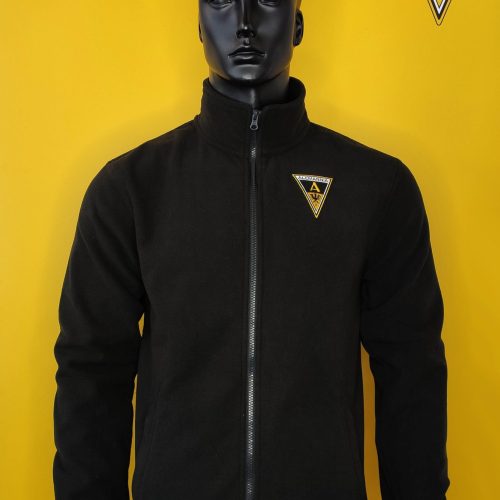 Mannequin wears a black zip-up jacket with a small Alemannia badge on the left chest, against a bright yellow background with a logo.