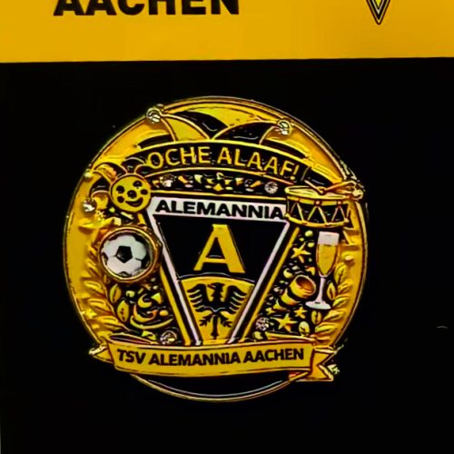Gold Alemannia Aachen enamel pin badge featuring the crest with A and banners on a black background.