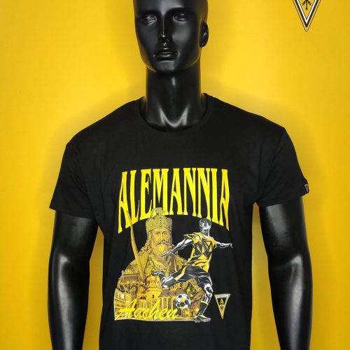 Black mannequin wearing a black T-shirt with a bold yellow 'ALEMANNIA' graphic against a bright yellow wall; crest logo visible in the top-right corner.