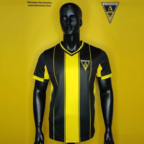 Black mannequin wearing a yellow-and-black striped soccer jersey with club crest on the chest against a yellow backdrop