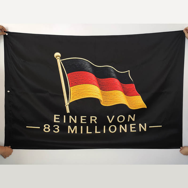 Black banner being held at the corners, featuring an embroidered German flag and the text 'EINER VON 83 MILLIONEN'.